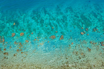 Fototapeta na wymiar Transparent sea water, top view. Aerial view of calm sea water. Top view of a clean ocean water near a coast.