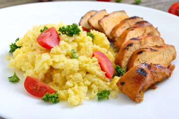 Grilled chicken breast and delicious millet porridge on a white plate. Close up