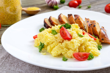 Grilled chicken breast and delicious millet porridge on a white plate on a wooden table