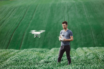 Young man piloting a drone on a spring field