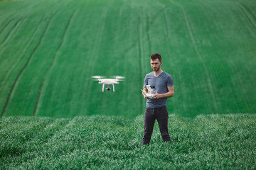 Young man piloting a drone on a spring field - 268970038