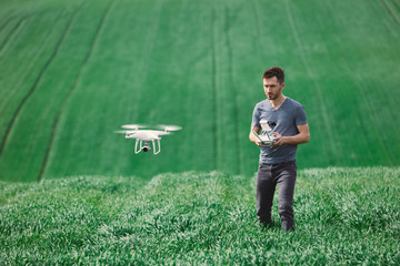 Young man piloting a drone on a spring field - 268970071