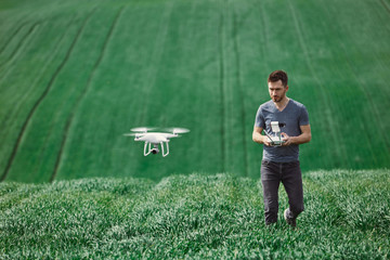 Young man piloting a drone on a spring field - 268970075
