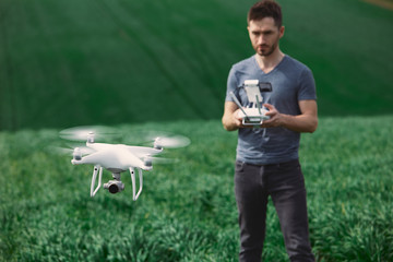 Young man piloting a drone on a spring field - 268970219