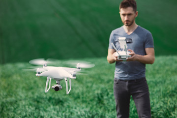 Young man piloting a drone on a spring field - 268970224