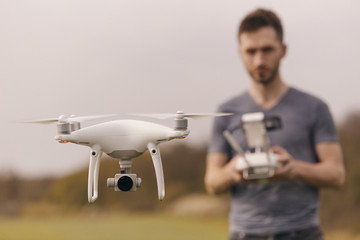 Young man piloting a drone on a spring field - 268970269