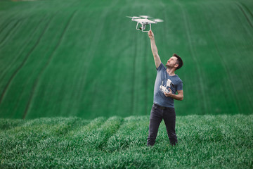 Young man piloting a drone on a spring field - 268970462