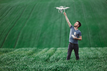 Young man piloting a drone on a spring field