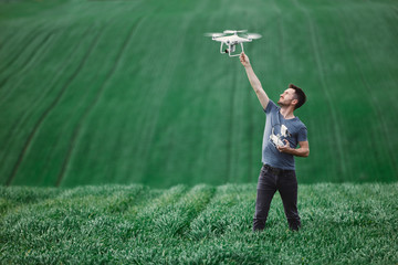 Young man piloting a drone on a spring field - 268970498