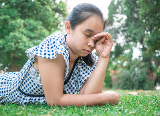 Asian young woman lying down on grass ground in the park and Irritate the eyes from dust. Space for your text.