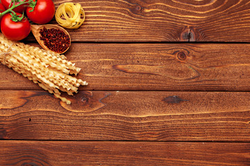 Pasta and ingredients on wooden background with copy space. Top view.