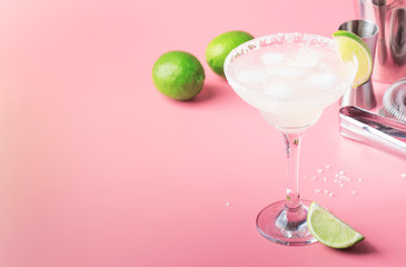 Classic margarita alcohol cocktail with tequila, liqueur, lime juice, sugar syrup, salt and ice, summer pink background, place for text