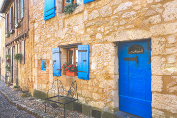 Fototapeta na wymiar Facade of stone houses with wooden doors and blue windows in Bergerac town, France