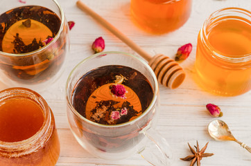 Composition with honey, tea and tea accessories on a white wooden background