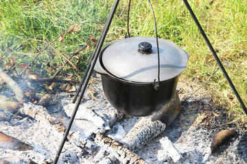 cooking delicious tasty food outdoors on fire in iron pot in summer in good weather with wood from...