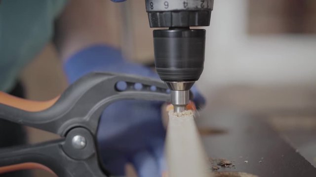 Unrecognized skill kraftsman making halls in the chipboard details with cordless screwdriver. Concept of hand manufacturing. Craftman works in a workshop.