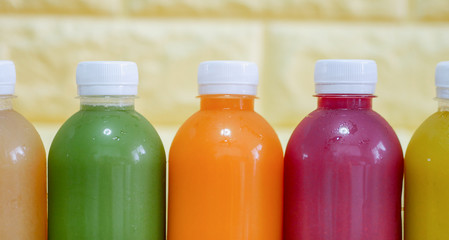 The bottles of cold pressed fruit and vegetables juice with yellow background.