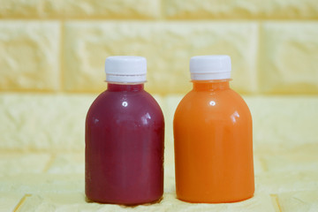 The bottles of cold pressed fruit and vegetables juice with yellow background.