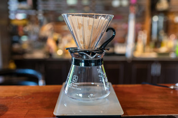 Measuring coffee drip with glass mug and paper filter on counter