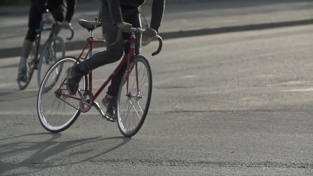 Cyclists ride fixie bicycles at city street. Ecological urban transport concept. Active lifestyle. Urban environment without car traffic.
