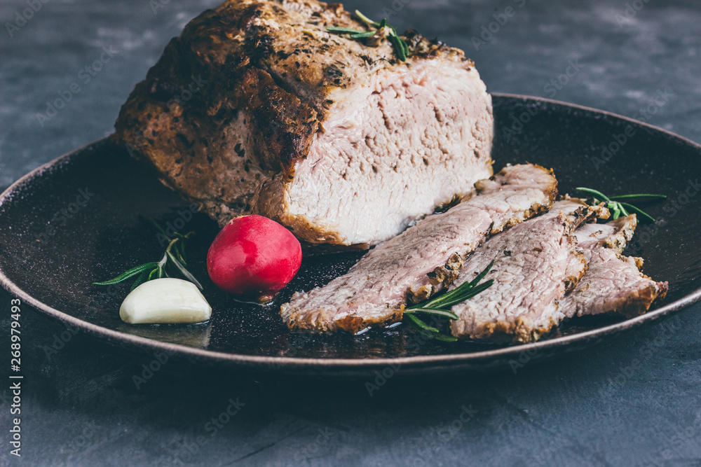 Poster Baked pork on a plate with rosemary on a blue concrete background close up dark style