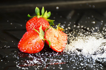 Strawberries in sugar on black background, photo,red sweet berry.