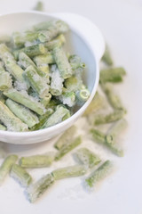Frozen green beans on a white plate. Healthy nutrition. Green vegetables. Preparation for cooking.