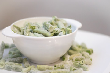 Frozen green beans on a white plate. Healthy nutrition. Green vegetables. Preparation for cooking.