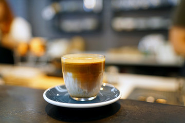Dirty Coffee - A glass of espresso shot mixed with cold fresh milk on wooden table and blurred background, Perfect for breakfast time.