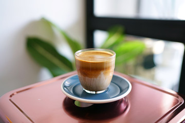 Dirty Coffee - A glass of espresso shot mixed with cold fresh milk on wooden table and blurred background, Perfect for breakfast time.