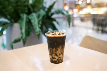 Bubble Milk Tea - A glass of Hojicha milk tea with black sugar syrup and black pearl (Boba) on blurred background, Taiwanese style.