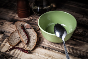 Bowl and spoon, bread and spices on burned wooden table. Preparing for traditional rural dinner. Toned