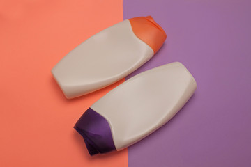 Beauty, decorative cosmetics bottles. Peach and purple colors background, flat lay, top view, minimalistic pop-art style