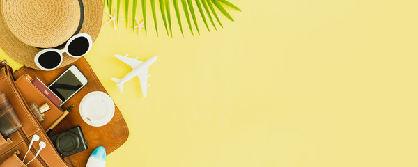 Top view of traveler accessories, tropical palm leaf and airplane on yellow banner background with...