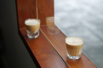 Dirty Coffee - A glass of espresso shot mixed with cold fresh milk on wooden table and blurred background, Perfect for breakfast time.