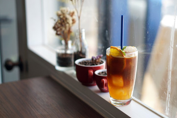 Iced coffee with orange - A glass of espresso shot mixed with orange juice and craft soda, topped with mint leaves on blurred background.