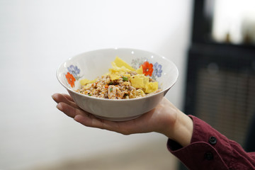 A bowl of dried noodle with fried wonton also known as spicy tom yum on table background and copy space, Traditional Thai food recipe, Popular street food of Thailand.