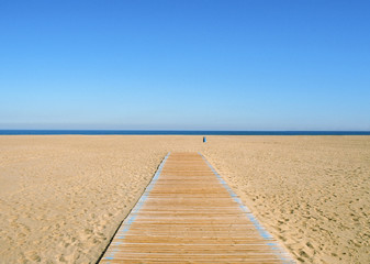 Fototapeta na wymiar Scene of sea, sky and empty beach with soft sand, wooden pathway and waste container