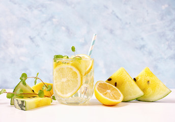 Cool and fresh yellow watermelon lemonade with ingredients on bright blue background. Vegeterian food concept. Detox
