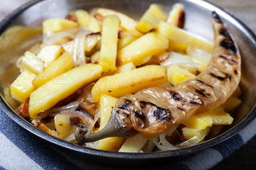 Delicious roast potatoes with onion and spices in a pan on kitchen towel on the old wooden table. Traditional rural dinner