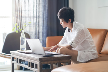 Asian woman working on laptop from home as freelancer