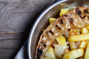 Delicious roast potatoes with onion and spices in a pan on kitchen towel on the old wooden table. Traditional rural dinner