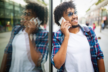 Close up portrait of handsome young man in city talking on smart phone