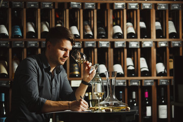 Sommelier degustating white wine poured in glass