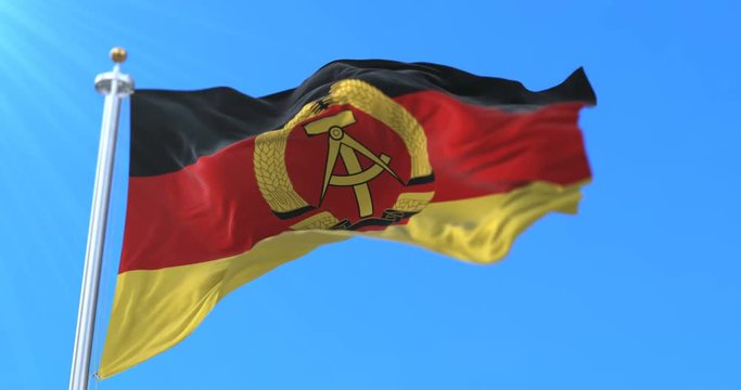 Flag of the German Democratic Republic or East Germany waving in blue sky. Loop