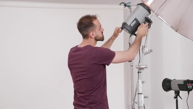 Professional photographer working and setting up the flashes before a fashion photo shoot in the studio