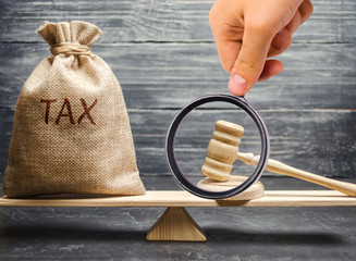Money bag with the word Tax and hammer judge on the scales. The concept of paying taxes and debt repayment. Register of taxpayers for property. Property taxes and mortgages. Gavel