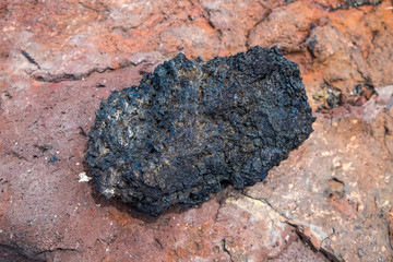 Naklejka premium Black lava rock from volcano on a pumice background.