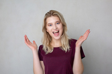 Excited smiling young woman spreading hands. Space for text