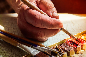 artist's tools, professional watercolor paints in a box, artist's brushes and brushes on a bright old table, soft focus